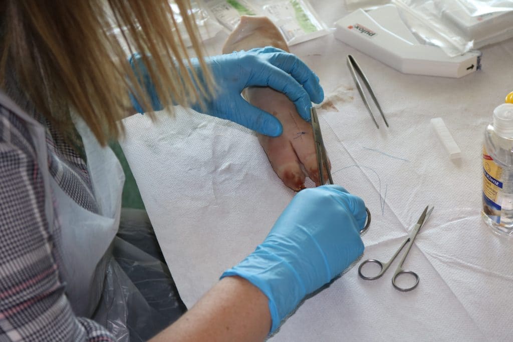 Woman suturing wound.